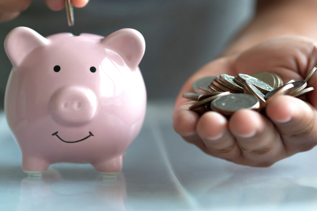 Person Holding Coins and Putting Them into Piggy Bank_Assisted Living Communities