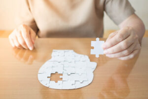 Hand of a senior putting a head-shaped puzzle together