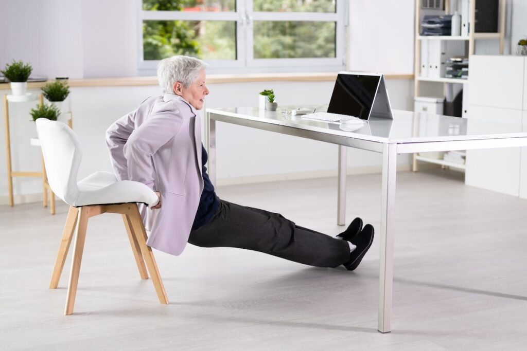 An older woman doing chair yoga