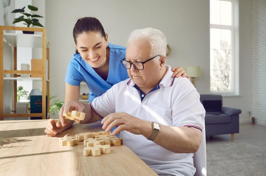 A female caregiver helping a senior with dementia solve a puzzle