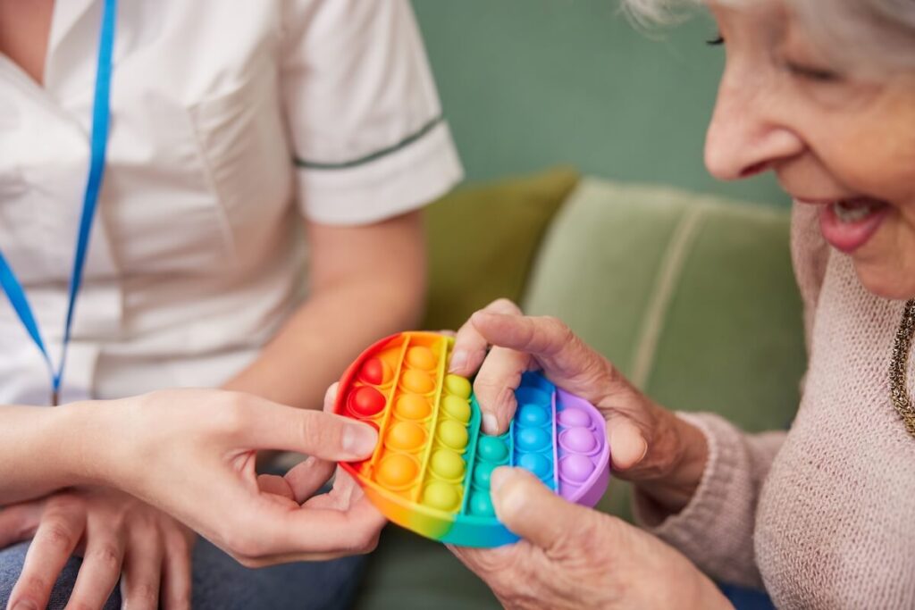 Happy older woman with dementia using a colorful toy for cognitive stimulation