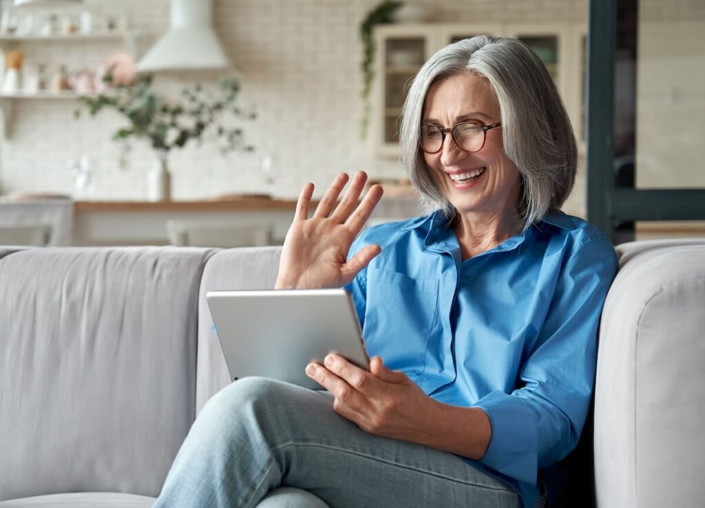 Older woman waving at her tablet