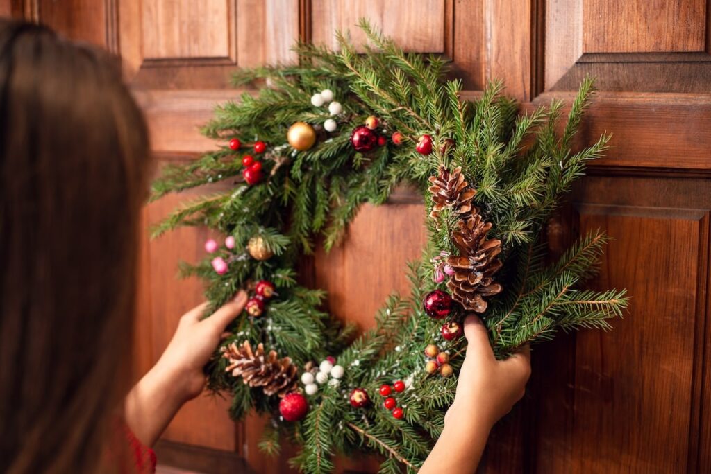 a woman puts a wreath on her door